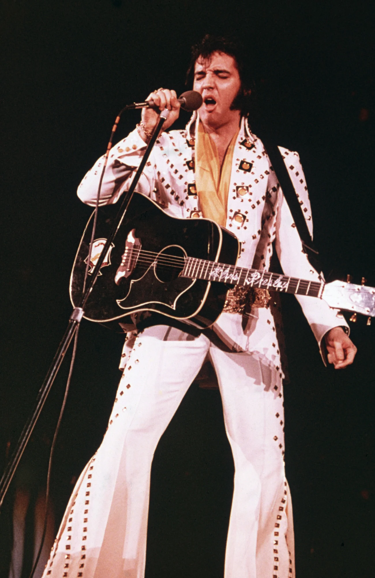 Elvis Presley mặc trang phục trắng và hát với guitar