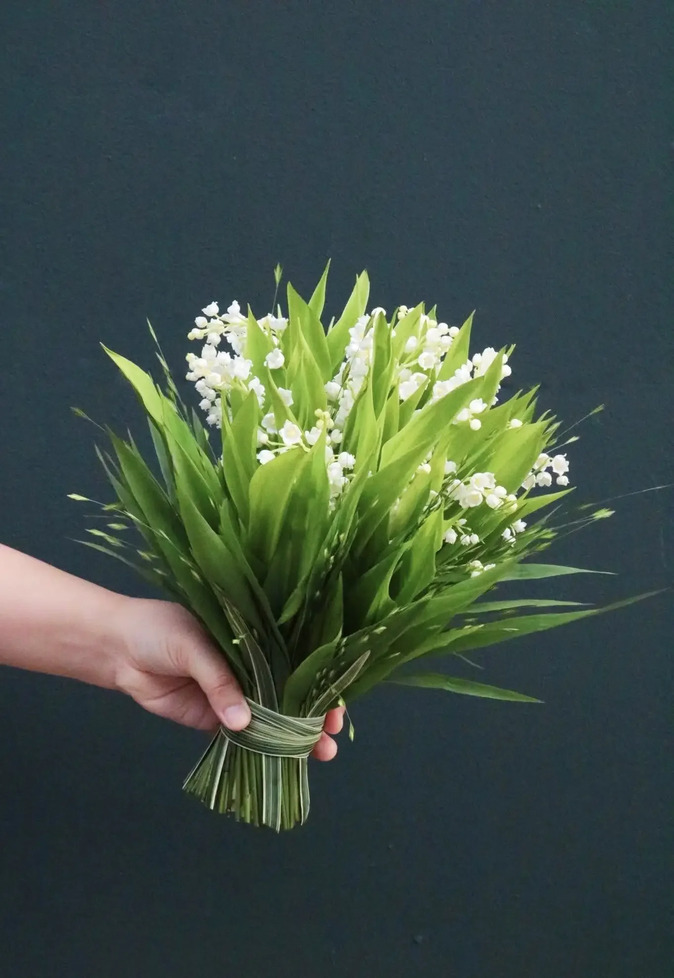 Bó hoa linh lan tươi thắm được cầm trên tay